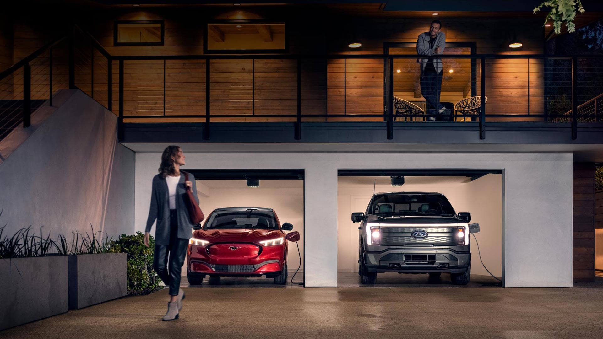 Woman walking out from home garage with a 2024 Mustang® Mach-E and Ford Lightning® truck in plugged-in and charging | Five Star Ford Lincoln in Aberdeen WA