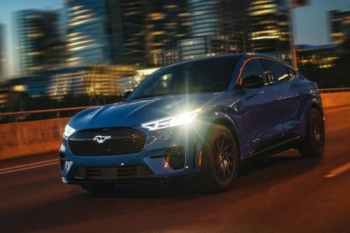 A 2024 Mustang® Mach-E being driven at night through a city street